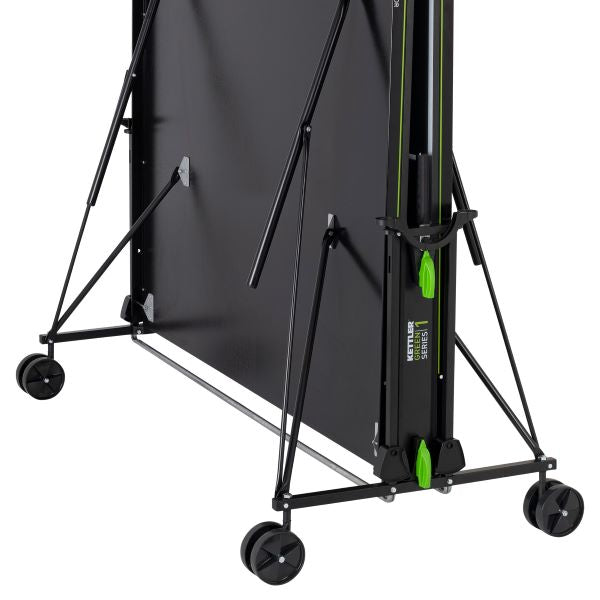 Seitenansicht der Kettler Tischtennisplatte K1 Indoor im zusammengeklappten Zustand, zeigt die stabile Konstruktion und die Mobilität durch die leichtgängigen Räder, ideal für platzsparende Lagerung.