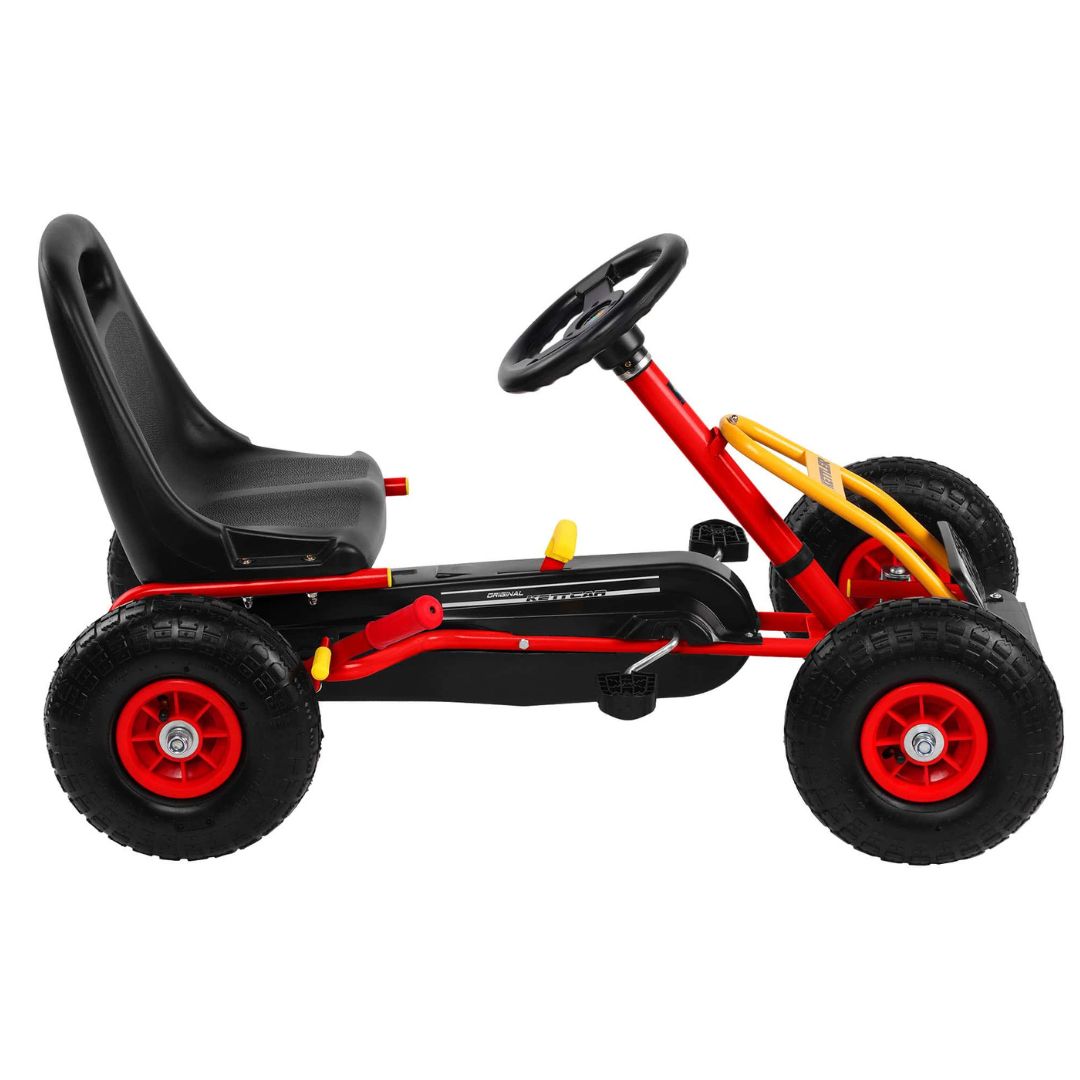 Seitenansicht des roten KETTLER Kettcars Retro, zeigt die komplette Länge des Fahrzeugs aus einer leicht anderen Perspektive.